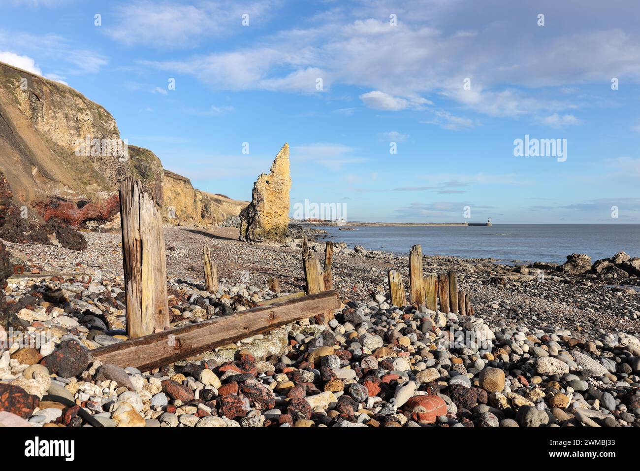 Magnesian Kalkstein Seestapel und wetterabgenutzt Timber Groynes am Seaham Chemical Beach, Durham Heritage Coast, Seaham, County Durham, Großbritannien Stockfoto