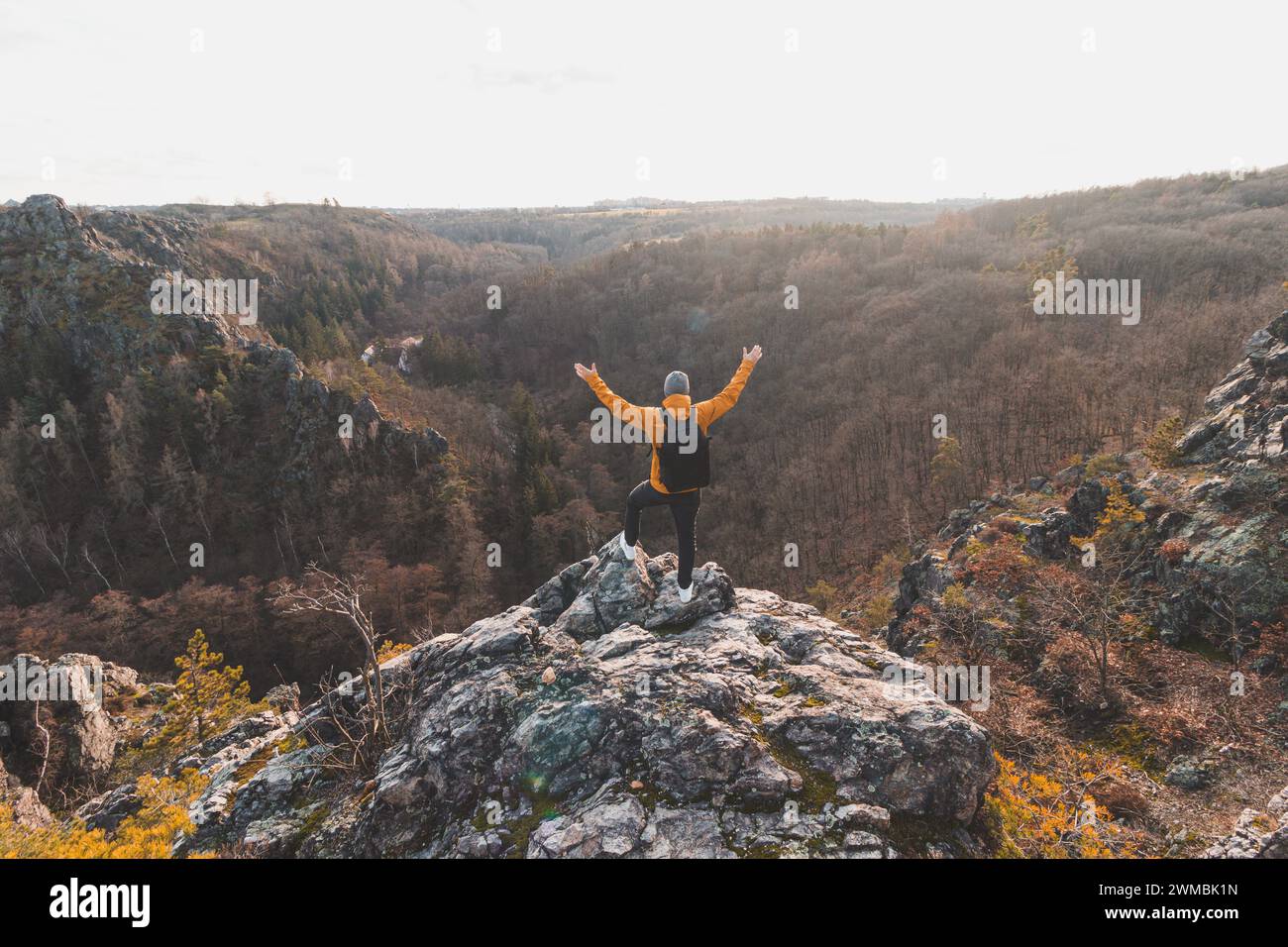 Reisende in einer gelben Jacke, die am Felsenrand steht, genießen einen Moment der Entspannung und einen Blick auf das Divoke-Sarky-Tal, Prag, Tschechische Repub Stockfoto