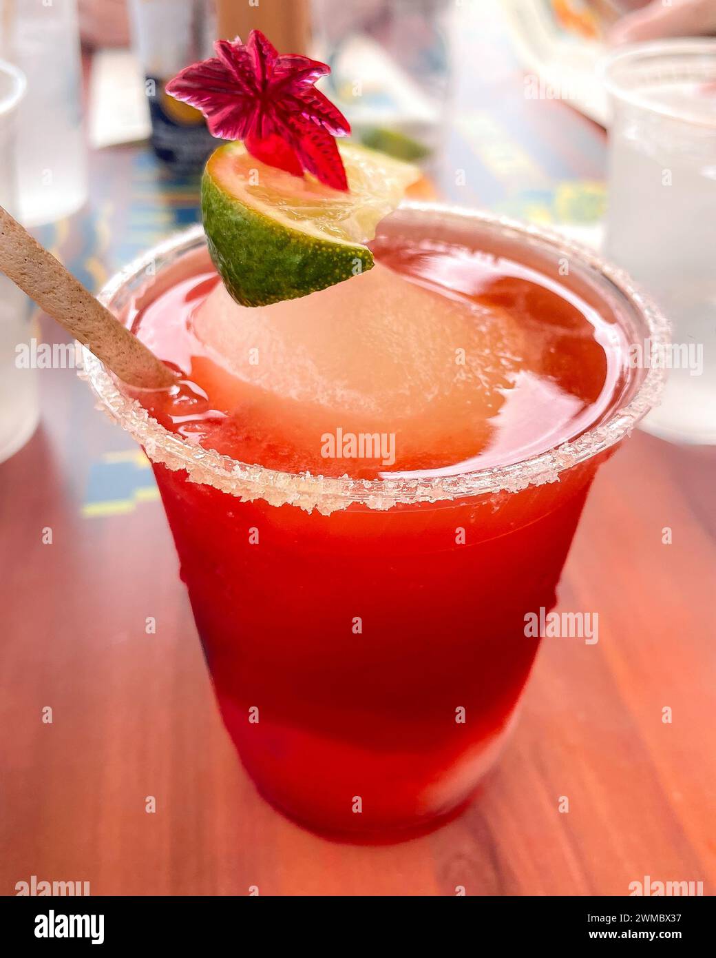 Ein frostiges Karmesinrot gefrorenes Erdbeer-Daiquiri, das auf dem Tisch sitzt, mit gesalztem Rand und einem lebendigen Limettenkeil verleiht ihm einen spritzigen Farbakzent. Abschließen des p Stockfoto