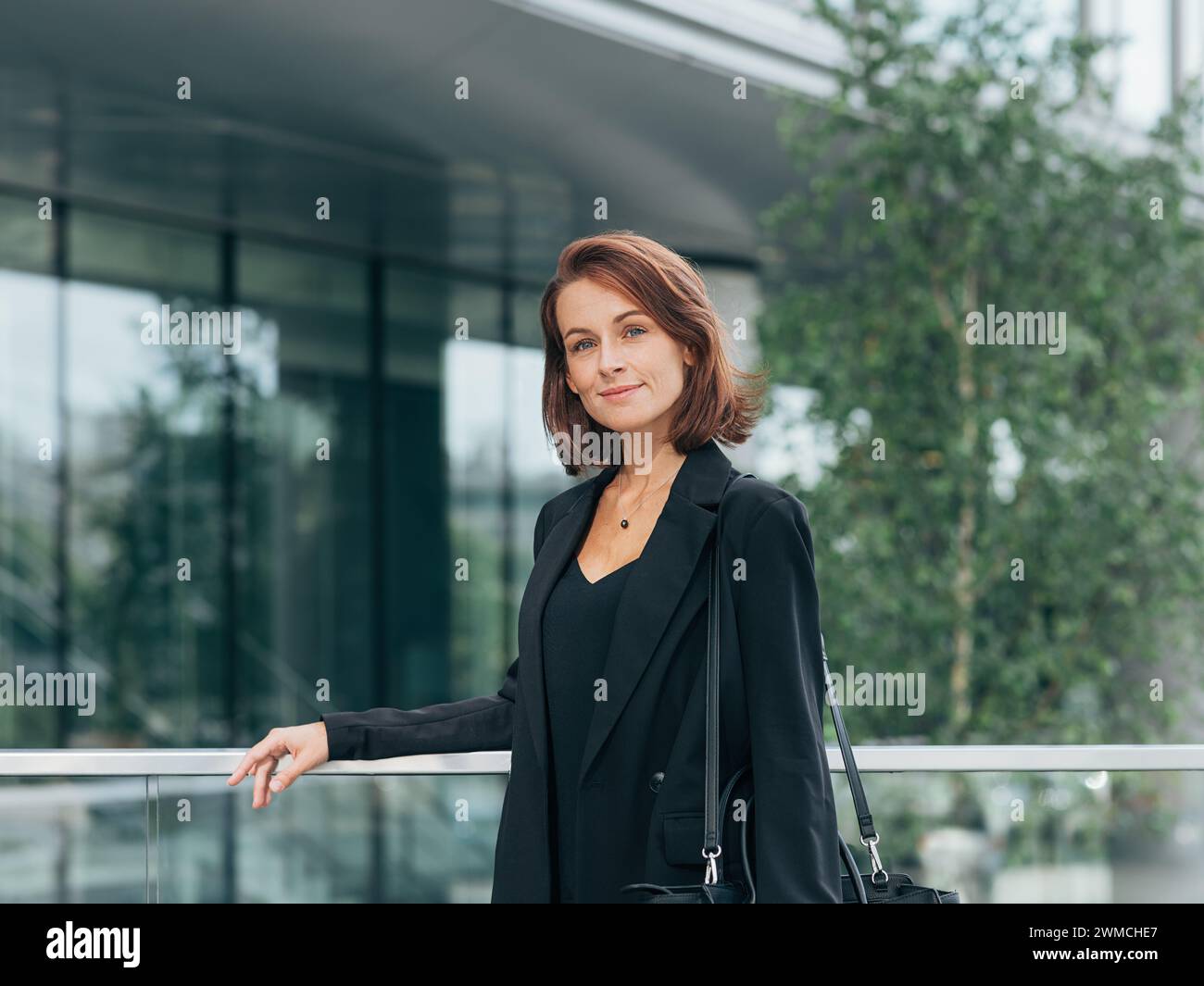 Eine Frau mittleren Alters mit Ingwerhaaren, die in einem Geschäftsgebäude gelandet ist, trägt schwarze formelle Kleidung Stockfoto