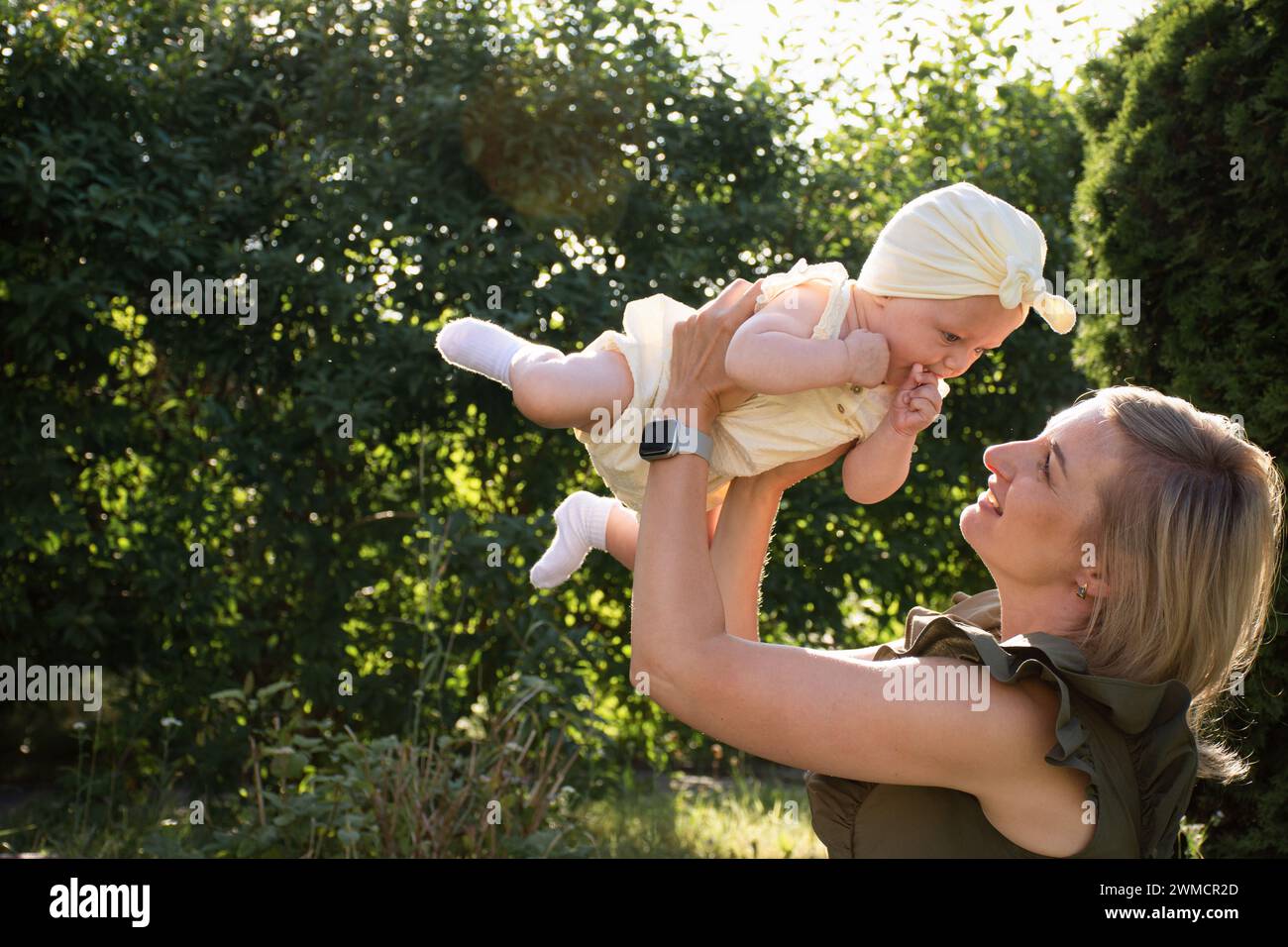 Mutter wirft ihr Baby in die Arme und lacht Stockfoto
