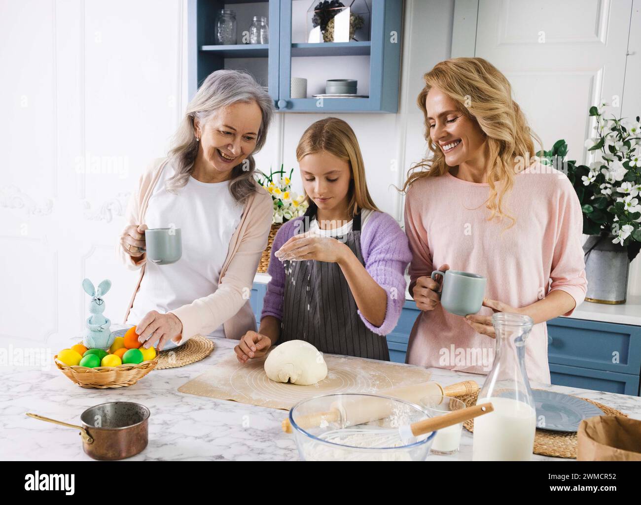 Großmutter, Mutter und Enkelin kommen zusammen, um in der gemütlichen Küche traditionelles Osterbrot für die Familientradition zu backen. Osterferien Stockfoto