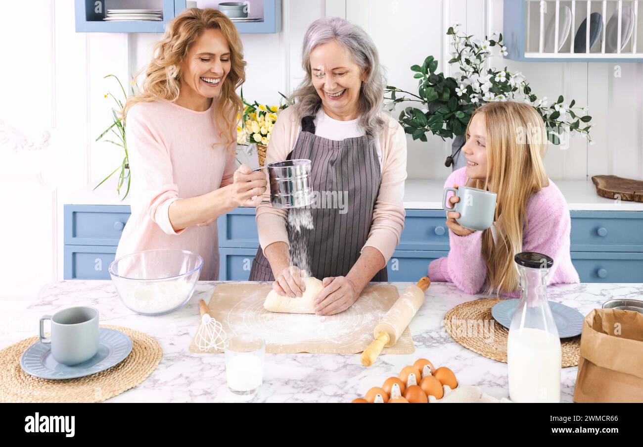 Drei Generationen von Frauen versammeln sich in der gemütlichen Küche, machen und Rollen Teig zusammen mit Lächeln und Lachen aus. Großmutter unterrichtet ihre Tochter und g Stockfoto