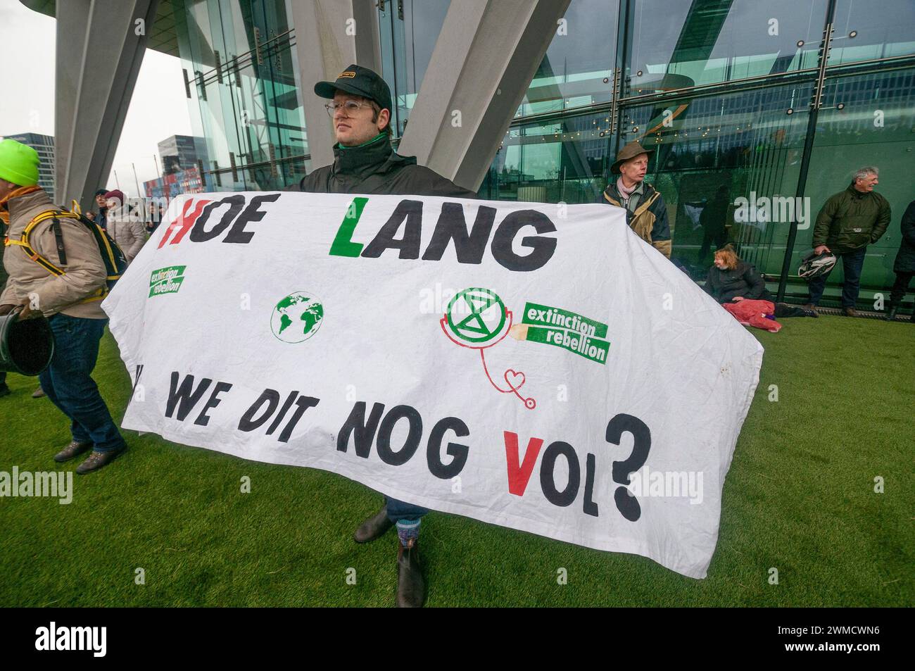 Aktivist der Extinction Rebellion steht gegenüber der Autobahn A10 mit einem Banner, das ihre Meinung zum Ausdruck bringt, während der Blockade der Autobahn. Extinction Rebellion, eine Blockade auf der Autobahn A10 in Amsterdam; 15 Minuten nachdem die ersten Demonstranten auf der Autobahn gelaufen waren, begann die Polizei mit Verhaftungen. Insgesamt wurden 326 Verhaftungen vorgenommen und 31 blieben in Haft. Die restlichen 295 wurden per Bus nach Amsterdam Noord transportiert und freigelassen. Kurz vor dem Polizeieinsatz wurden die Aktivisten gewarnt, dass Schlagstöcke und Pfefferspray verwendet würden, obwohl dies nicht vorkam. Der Dämon Stockfoto