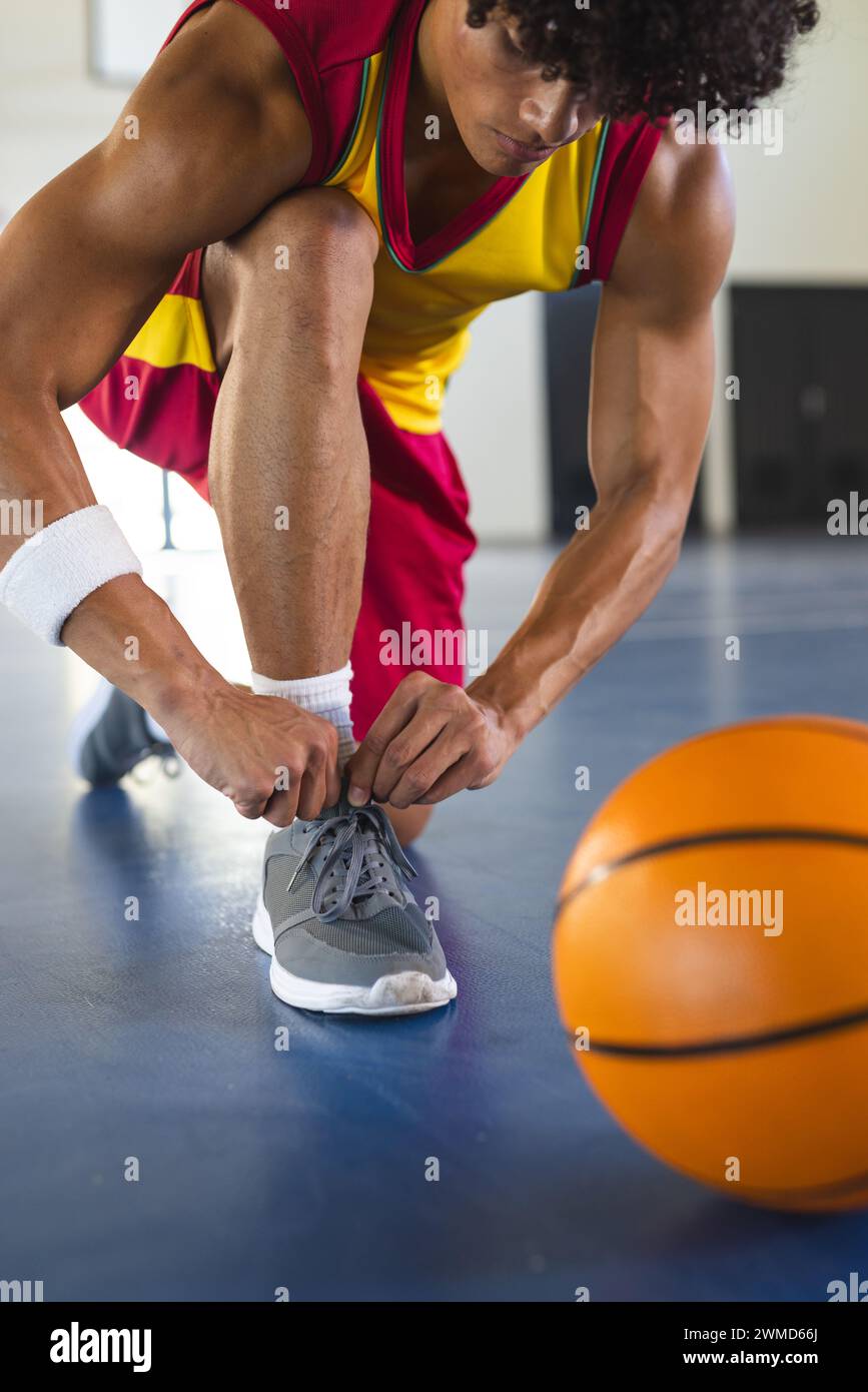 Ein junger birassischer Mann bindet seine Schnürsenkel in einem Fitnessstudio Stockfoto