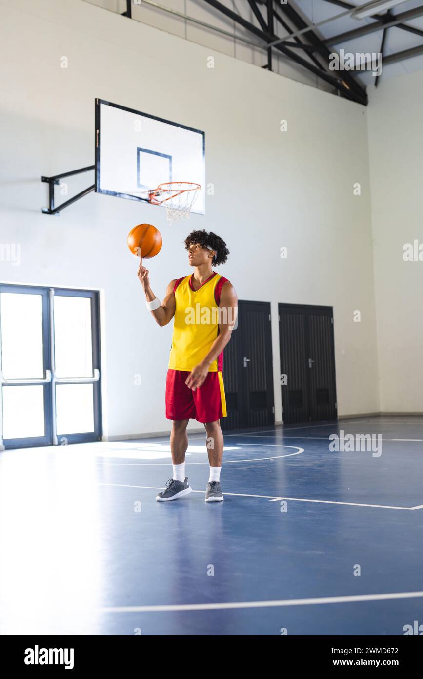 Ein junger birassischer Mann übt Basketball auf einem Hallenplatz Stockfoto