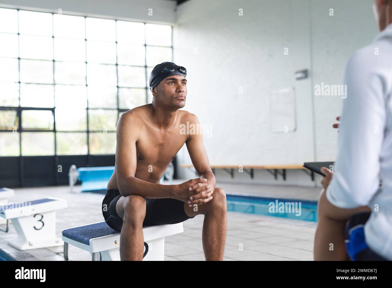 Ein junger männlicher Sportler sitzt am Pool Stockfoto