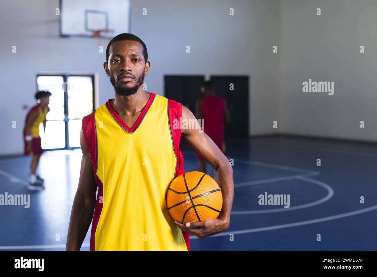 Afroamerikaner hält einen Basketball auf dem Platz, mit Kopierraum Stockfoto