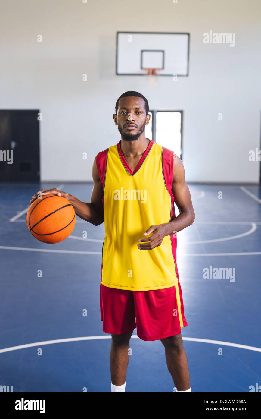 Ein afroamerikanischer Mann posiert selbstbewusst auf einem Basketballfeld Stockfoto