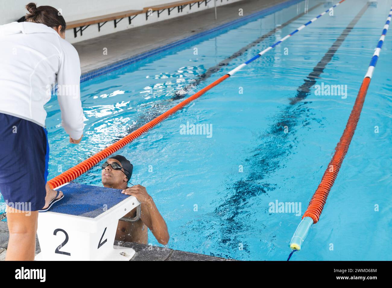 Der Schwimmer erhält die Anleitung von seinem Trainer am Pool, mit Platz für Kopien Stockfoto