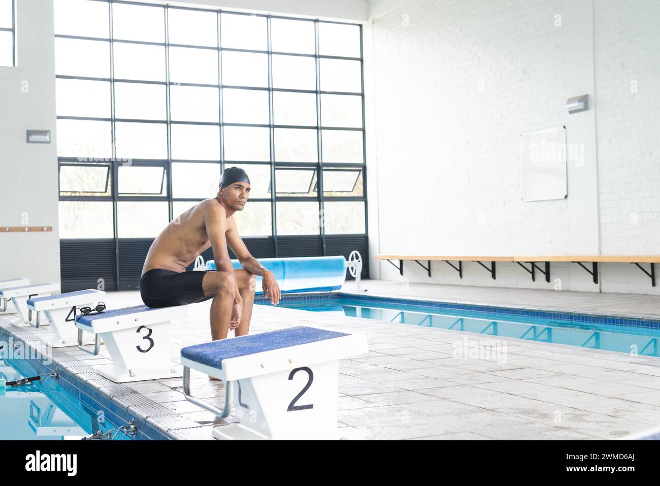 Ein junger männlicher Sportler sitzt am Pool, mit Kopierraum Stockfoto