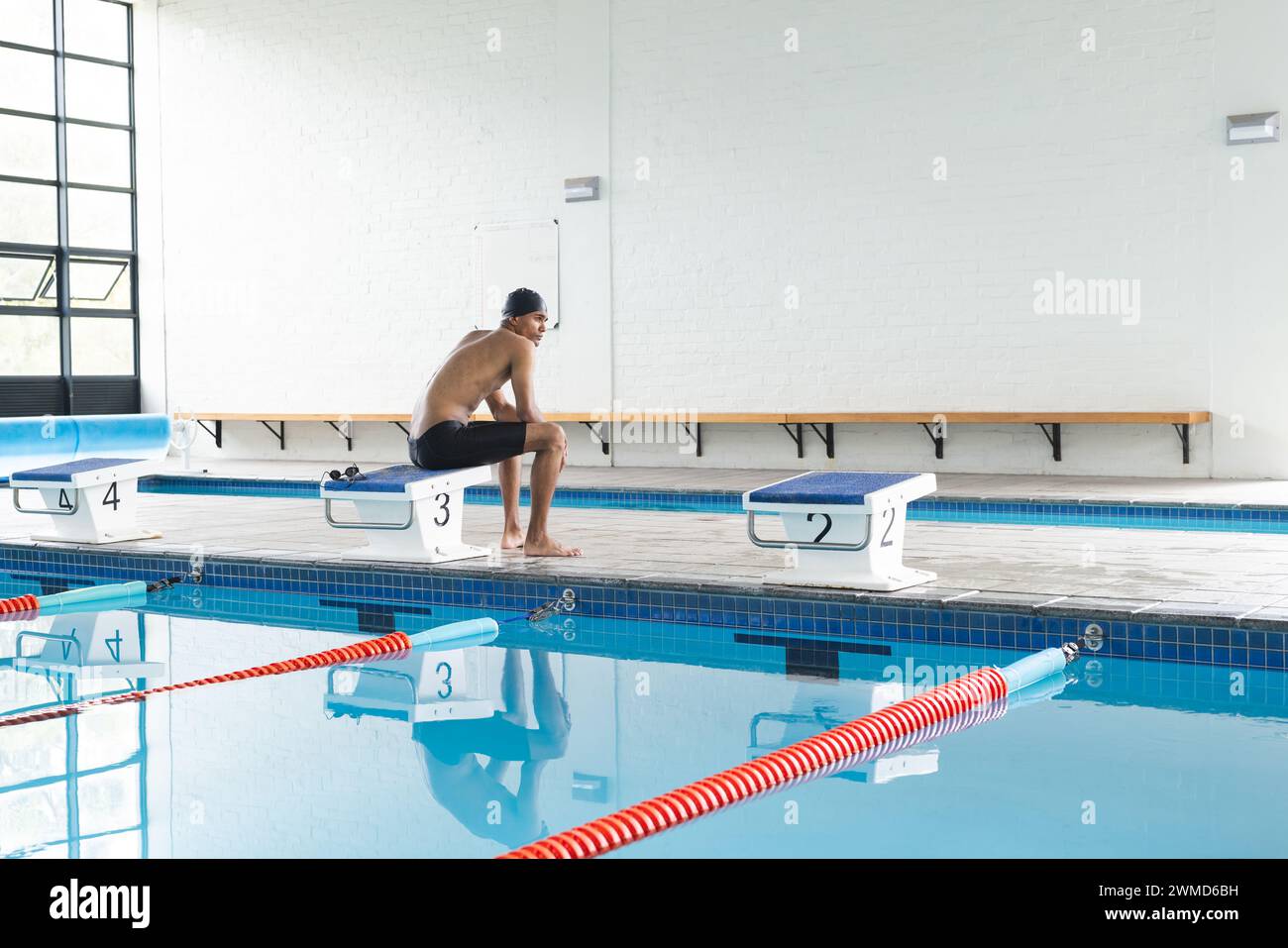 Junge männliche Sportlerinnen bereiten sich auf das Tauchen in einem Hallenbad mit Kopierraum vor Stockfoto