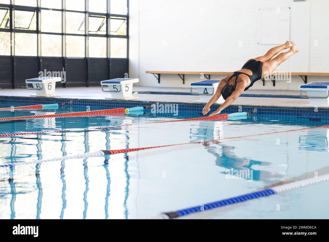 Eine weiße Sportlerin taucht in ein Schwimmbad in einem Sportzentrum ein Stockfoto