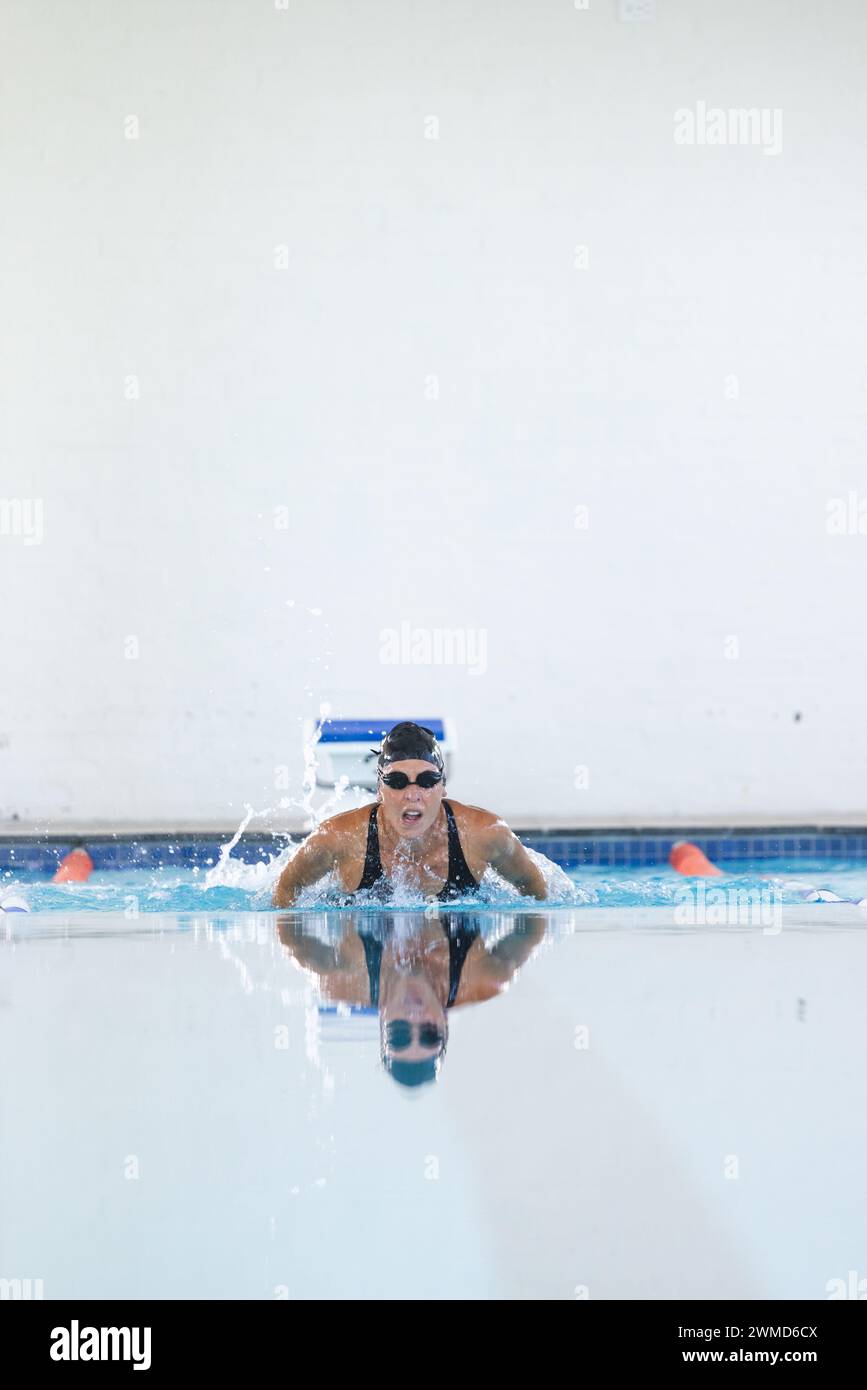 Die weibliche Athletin schwimmt in einem Hallenbad Stockfoto