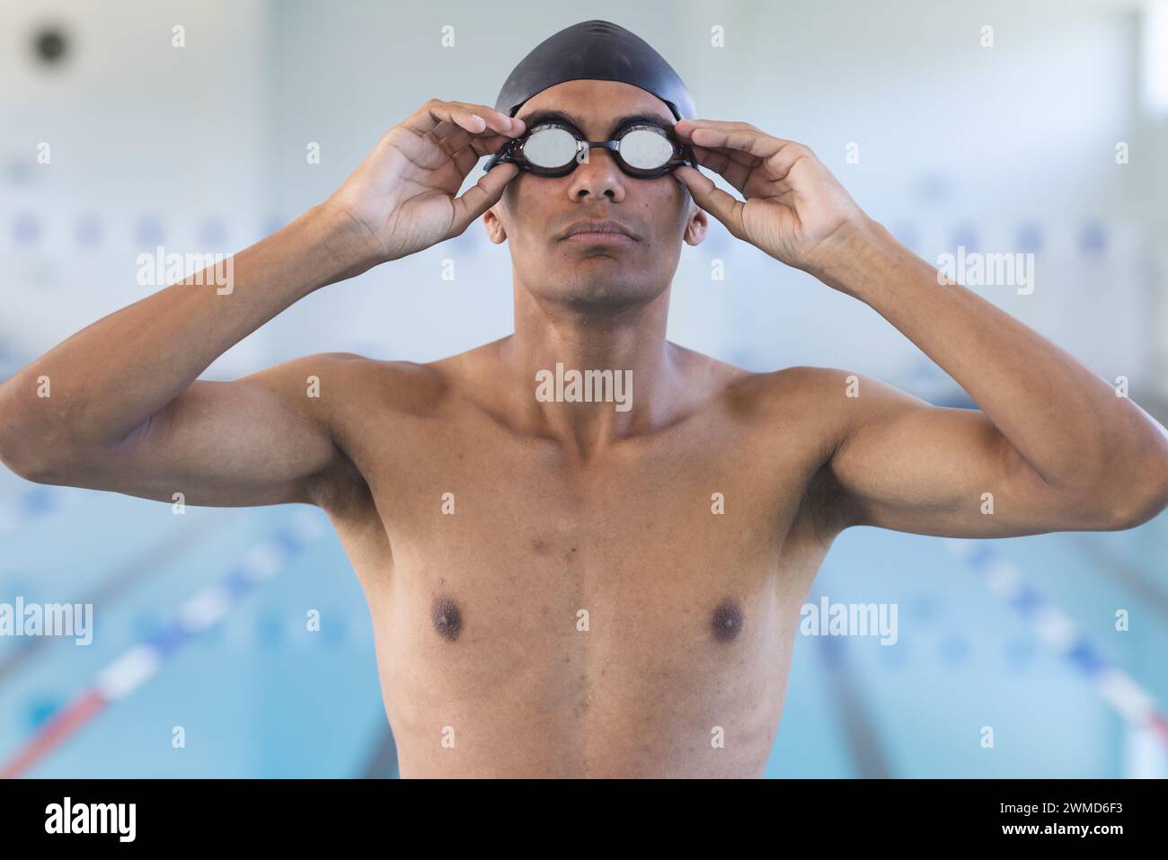 Ein junger männlicher Sportler passt seine Schwimmbrille am Pool an Stockfoto
