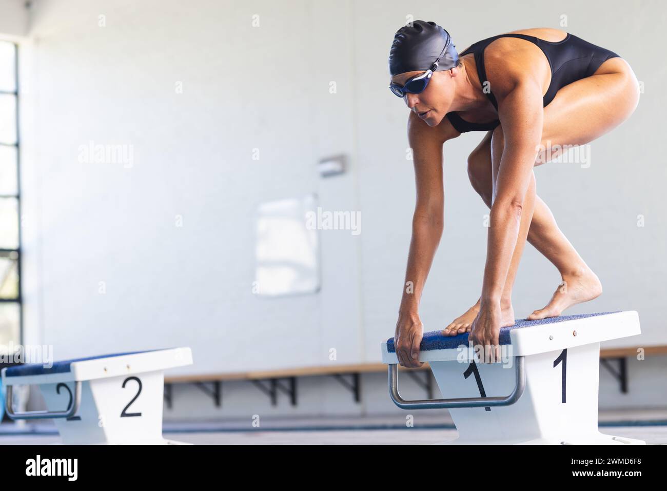 Die weibliche weibliche Sportlerin aus dem Kaukasus bereitet sich darauf vor, bei einem Wettkampf in einen Pool zu tauchen Stockfoto