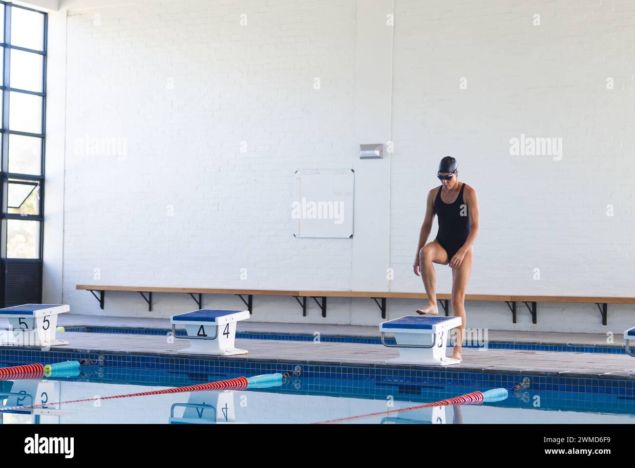 Kaukasische Sportlerinnen bereiten sich auf das Tauchen in einem Hallenbad vor Stockfoto