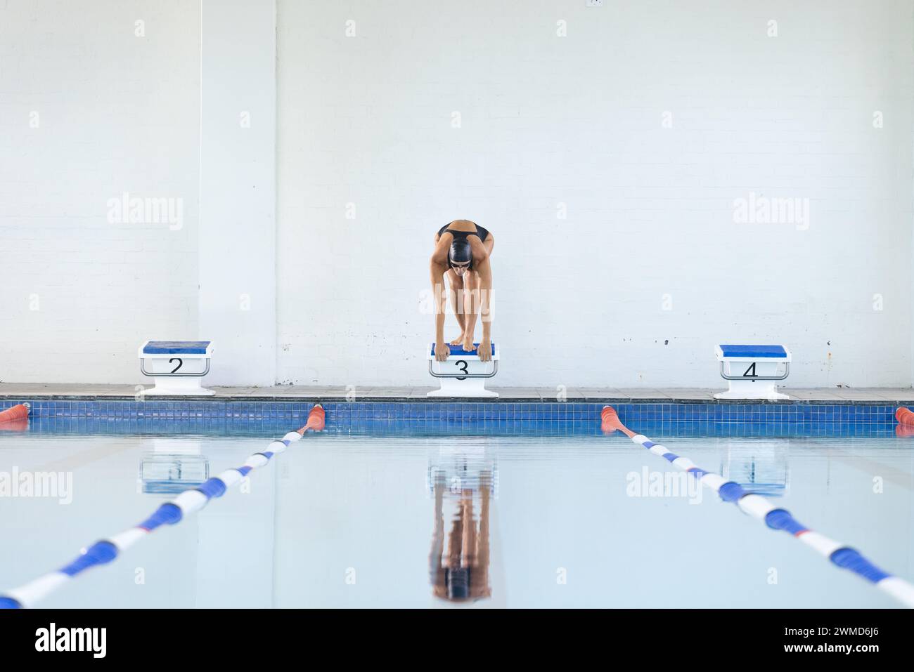 Ein Schwimmer bereitet sich auf das Tauchen in einem Hallenbad mit Kopierbereich vor Stockfoto