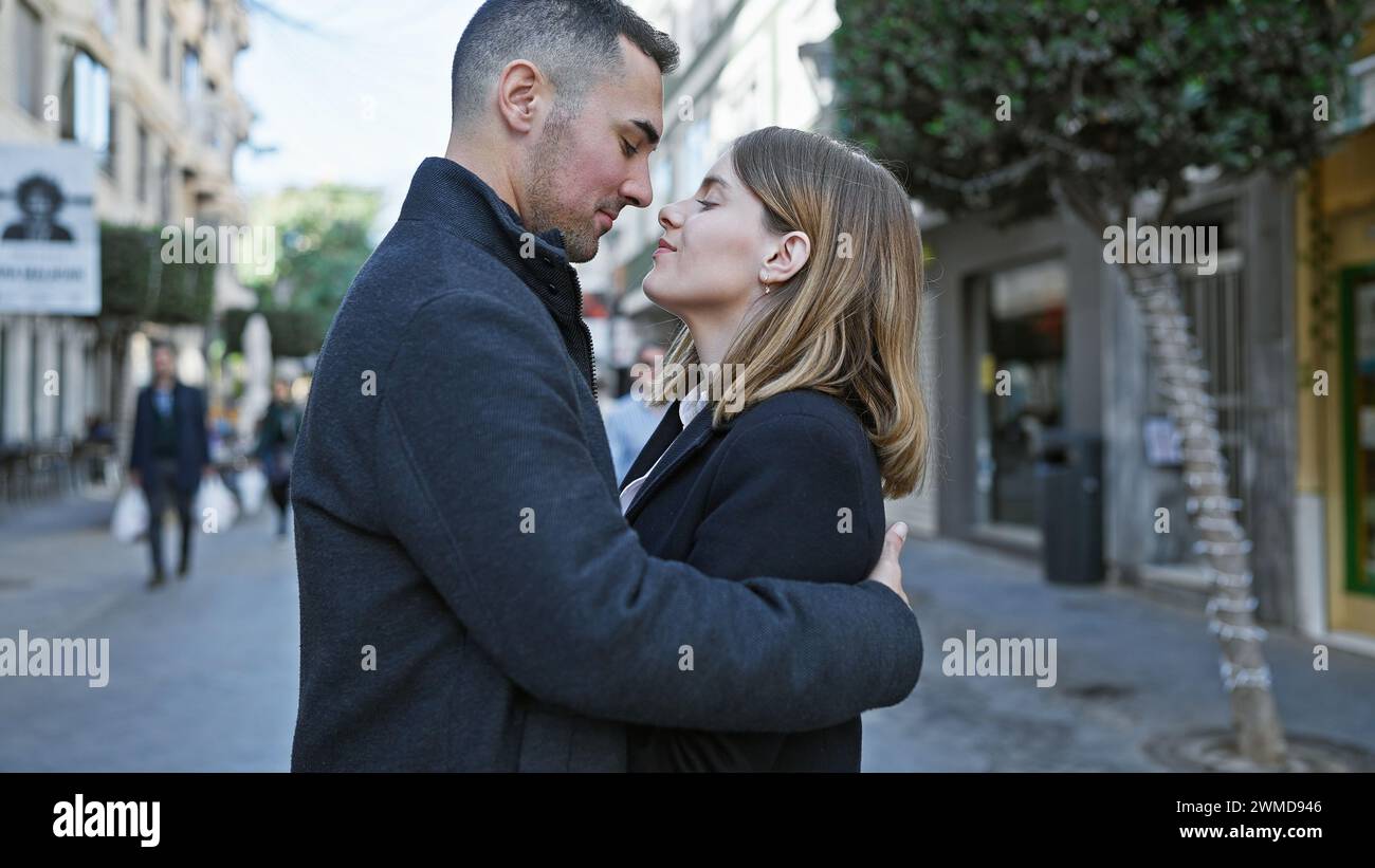 Ein liebevolles Paar umarmt sich in einer geschäftigen Stadtstraße und weckt inmitten des Trubels der Stadt romantische Gefühle. Stockfoto