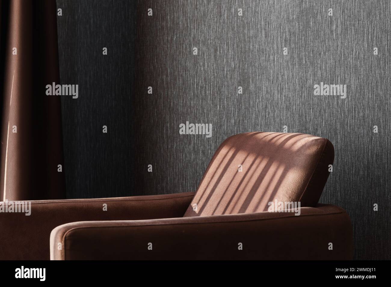 An einem sonnigen Tag steht ein komfortabler Luxussessel in einem leeren Raum vor der grauen Wand Stockfoto