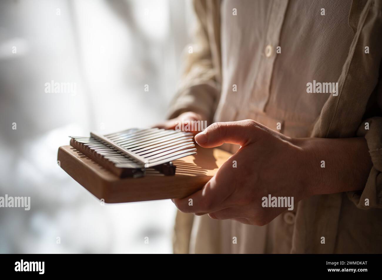 Ethnisches Musikinstrument aus Kalimba. Hände spielen Entspannungsmelodie auf Metalltasten und erzeugen Klänge. Stockfoto