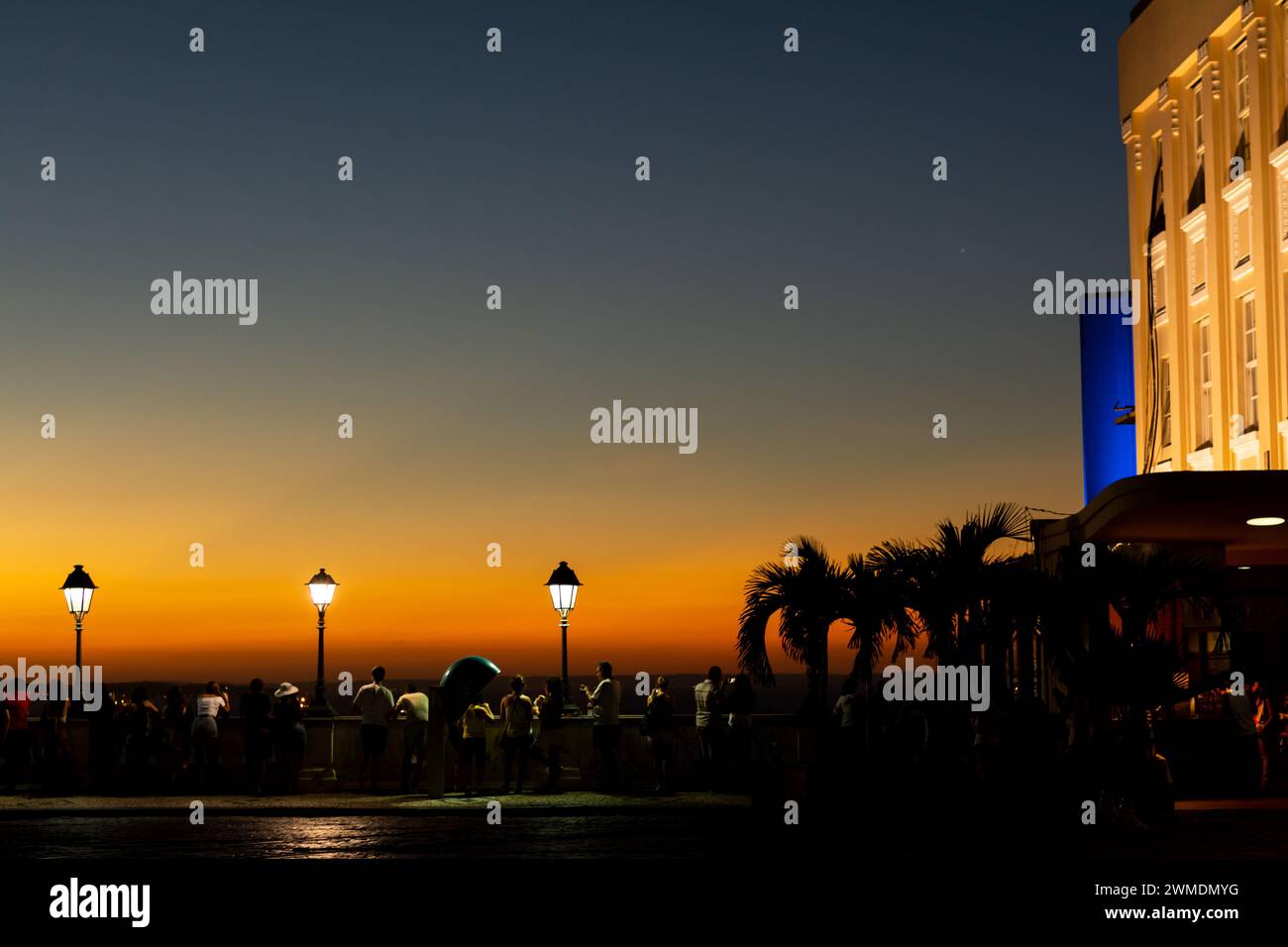 Salvador, Bahia, Brasilien - 21. April 2015: Silhouette von Touristen und Laternenpfosten bei Sonnenuntergang auf dem Platz Tome de Souza in der Stadt Salvador, Bahia. Stockfoto