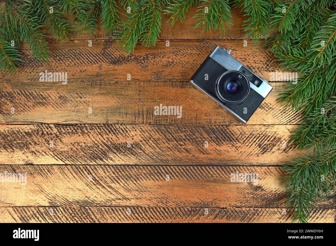 Die alte Kamera auf hölzernem Hintergrund und Zweige von Weihnachtsbaum. Weihnachtshintergrund. Nostalgie. Erinnerungen. Vergangenheit. Neujahr. Draufsicht. Nahaufnahme. Stockfoto