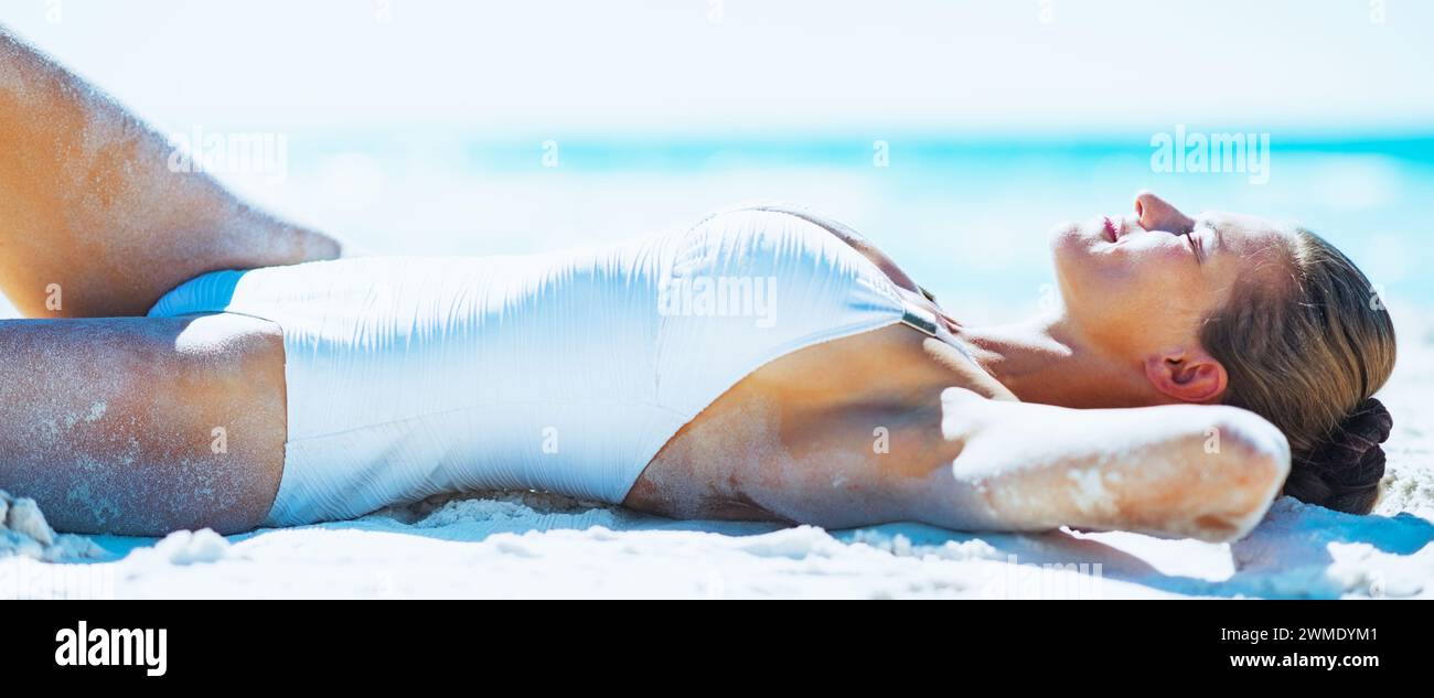 Glückliche junge Frau im Badeanzug am Strand bräunen Stockfoto