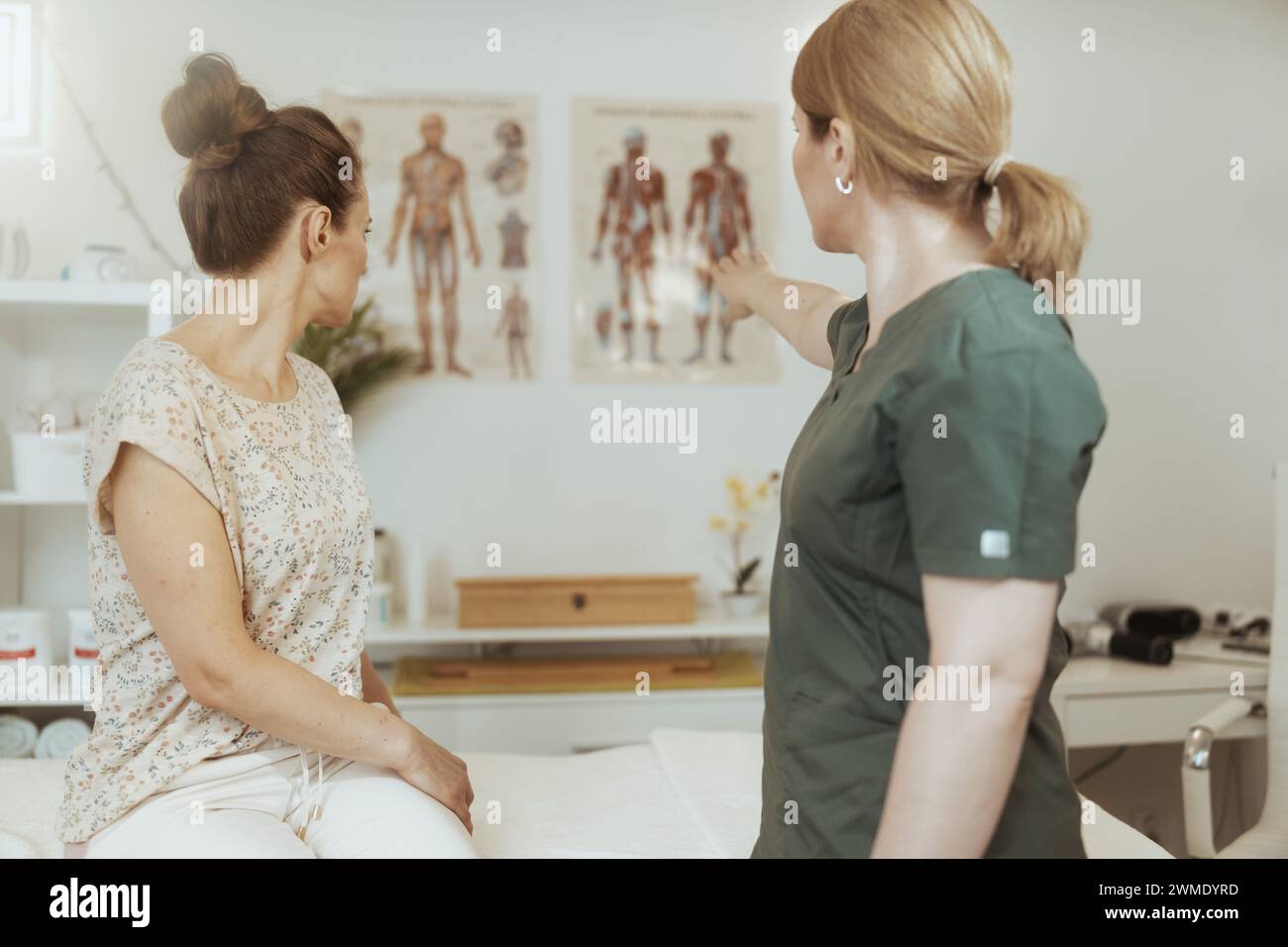 Gesundheitszeit. Von hinten gesehen Massagetherapeutin im Massagekabinett führt Erziehungstraining durch. Stockfoto