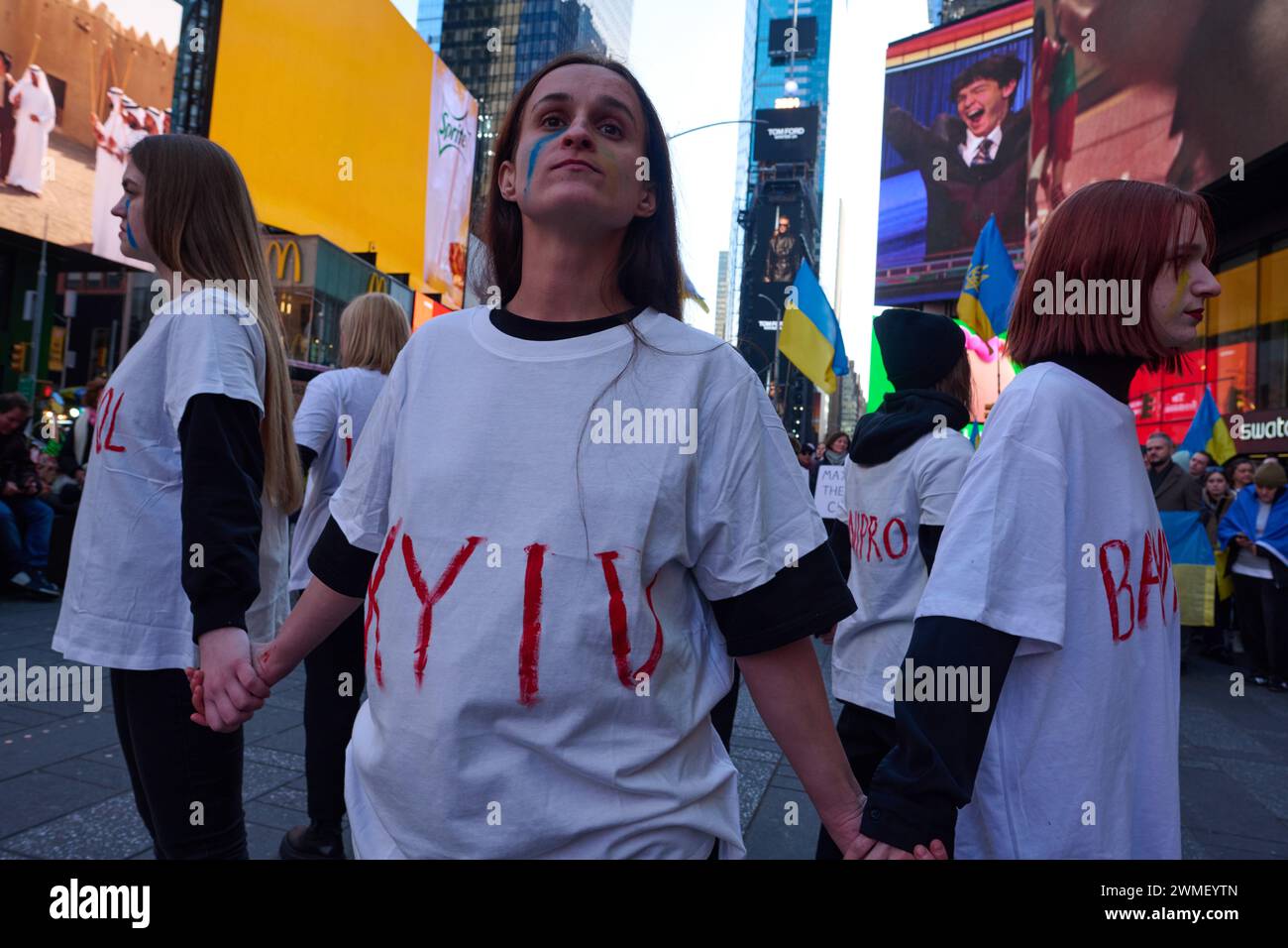 New York, New York, USA. Februar 2024. Eine Gruppe von Frauen steht in einem Kreis und hält Hände, trägt Hemden mit den Namen der ukrainischen Städte, die von Russland bei einer Kundgebung am Times Square eingefallen sind, die das zweite Jahr seit Russlands Invasion in die Ukraine markiert. (Kreditbild: © Edna Leshowitz/ZUMA Press Wire) NUR REDAKTIONELLE VERWENDUNG! Nicht für kommerzielle ZWECKE! Stockfoto