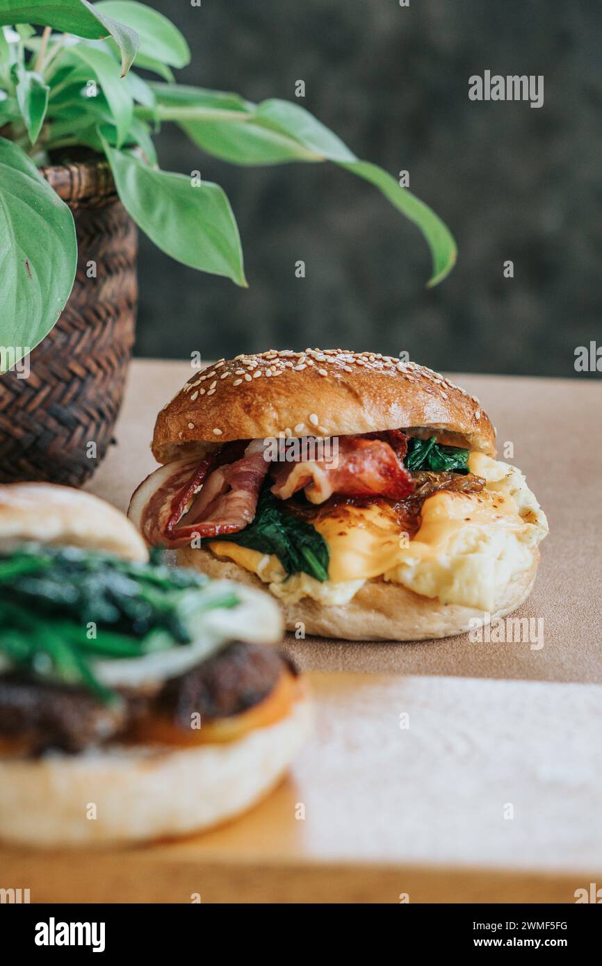 Ein Frühstücksbagel-Sandwich mit Rührei, Spinat und Käse auf einem Teller Stockfoto