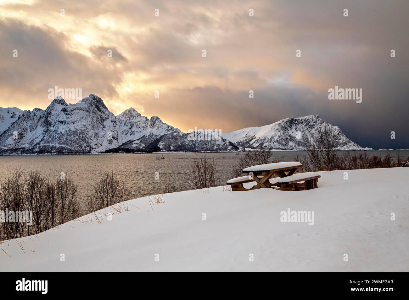 Eine verschneite Bank vor dem Sonnenuntergang mit Bergen auf den Vesteralen Stockfoto