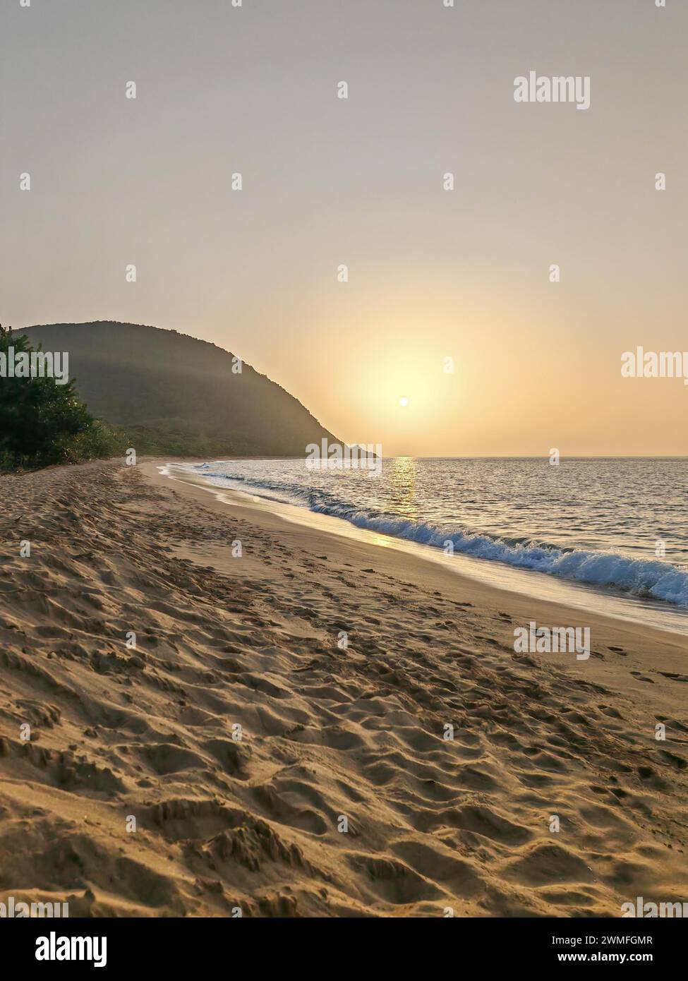 Blick über einen Strand, die Küste und das Meer bei Sonnenuntergang. Im Vordergrund der leere Sandstrand Grande Anse, Basse Terre, Guadeloupe, Französische Antillen Stockfoto