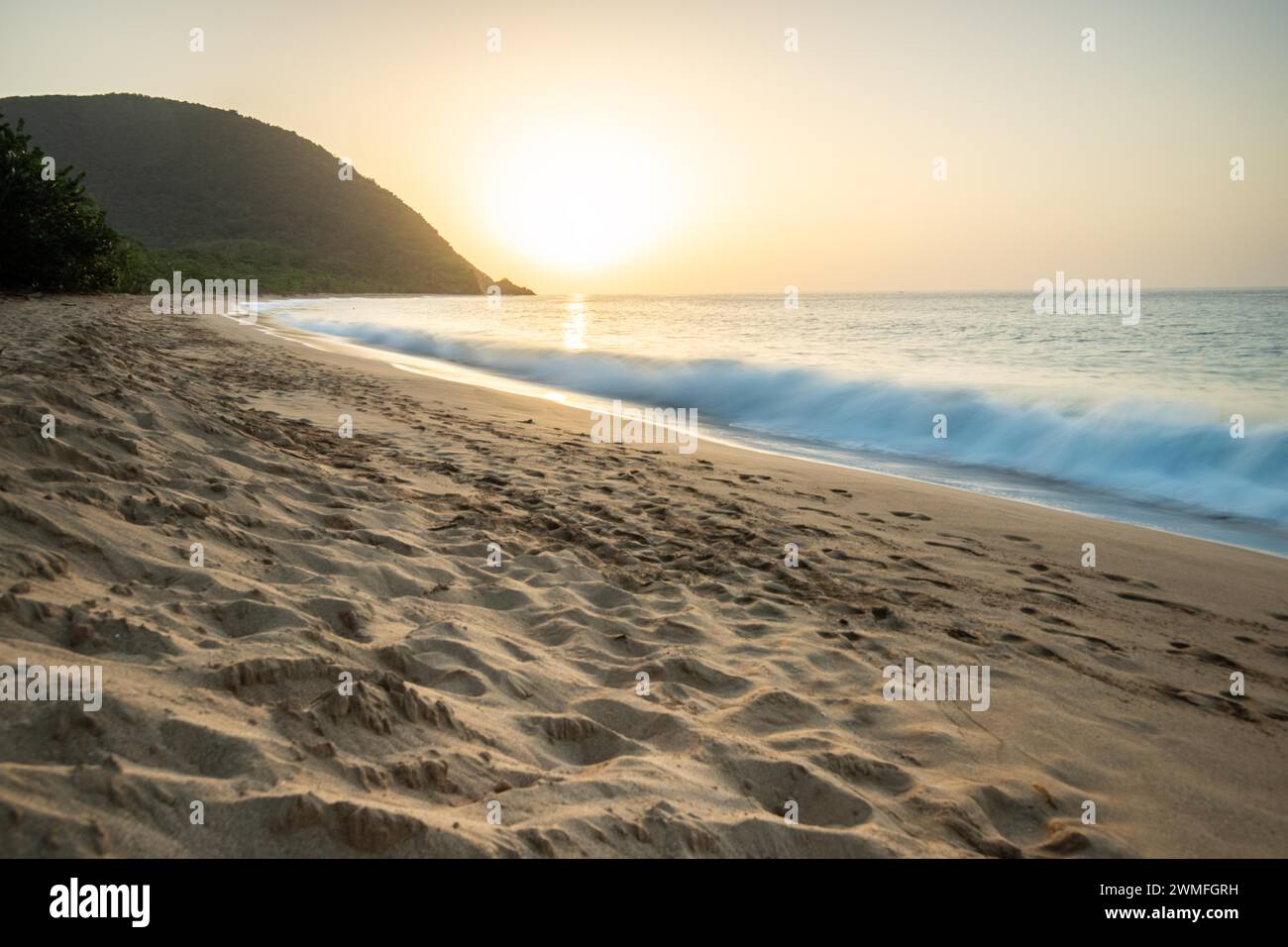 Blick über einen Strand, die Küste und das Meer bei Sonnenuntergang. Im Vordergrund der leere Sandstrand Grande Anse, Basse Terre, Guadeloupe, Französische Antillen Stockfoto