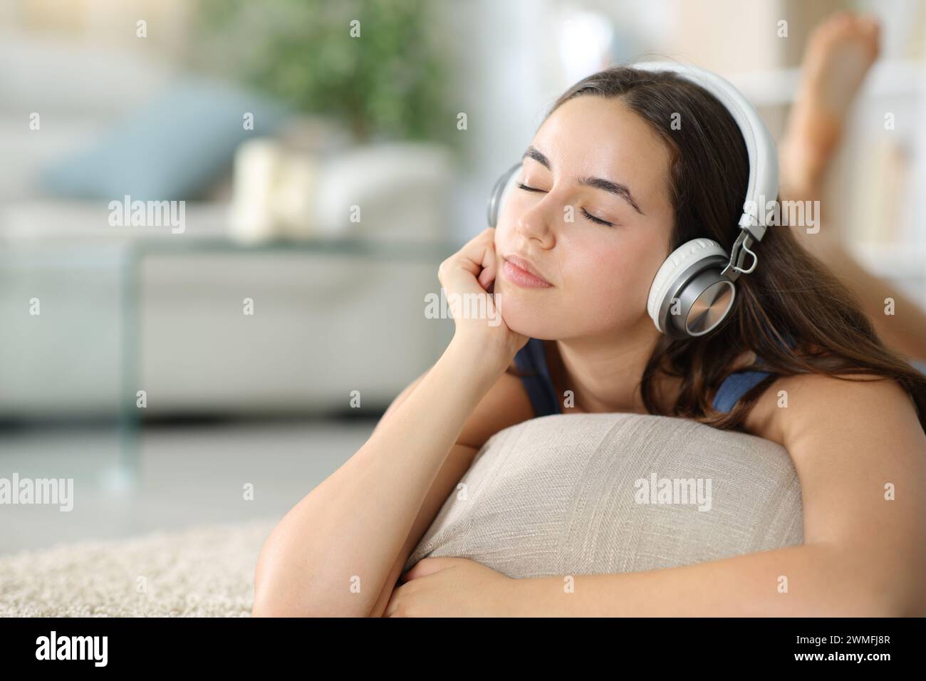 Entspannte Frau, die Kopfhörer trägt und zu Hause chillige Musik auf dem Boden hört Stockfoto