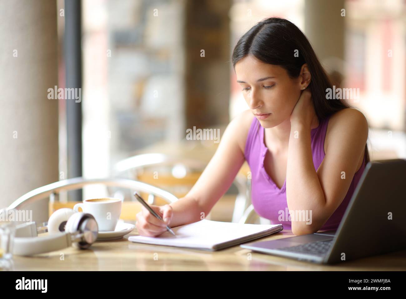Ernsthafter Student, der auf einer Coffee-Shop-Terrasse studiert, liest Notizen Stockfoto
