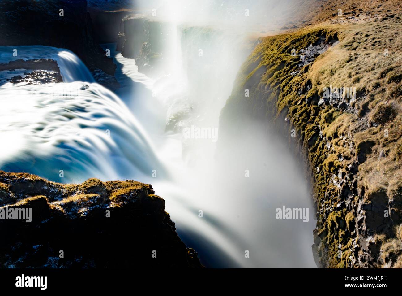 Von oben aus verwandelt sich der mächtige und schaumige Wasserfall in einen ansteigenden Dampf bei atmosphärischem Druck, während er durch raue felsige vulkanische Klippen in den Bergen fließt Stockfoto