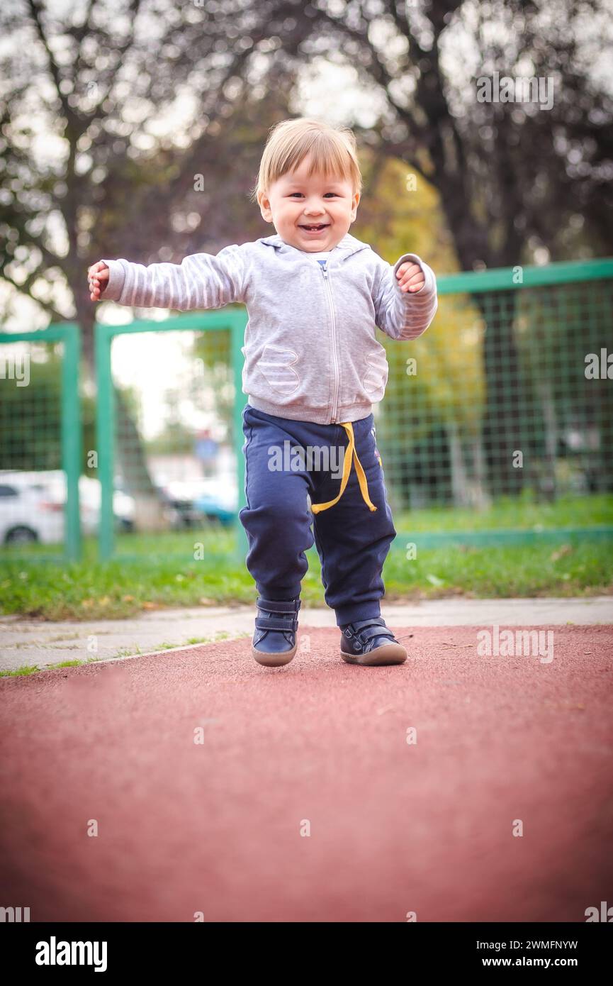 Fröhlicher, fröhlicher und lächelnder Junge läuft fröhlich auf dem Kinderspielplatz herum und erkundet die Wunder der Natur. Kind, Glück und Menschen c Stockfoto
