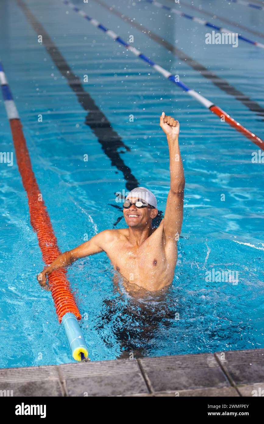 Junger männlicher Sportler, der mit birassischer Rasse schwimmt, feiert den Sieg in einem Schwimmbad Stockfoto