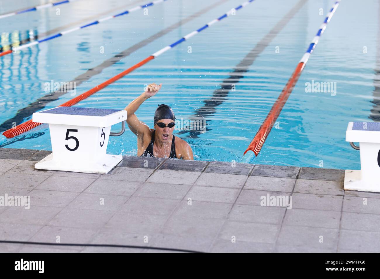 Die kaukasische Sportlerin feiert den Sieg bei einem Schwimmwettbewerb Stockfoto