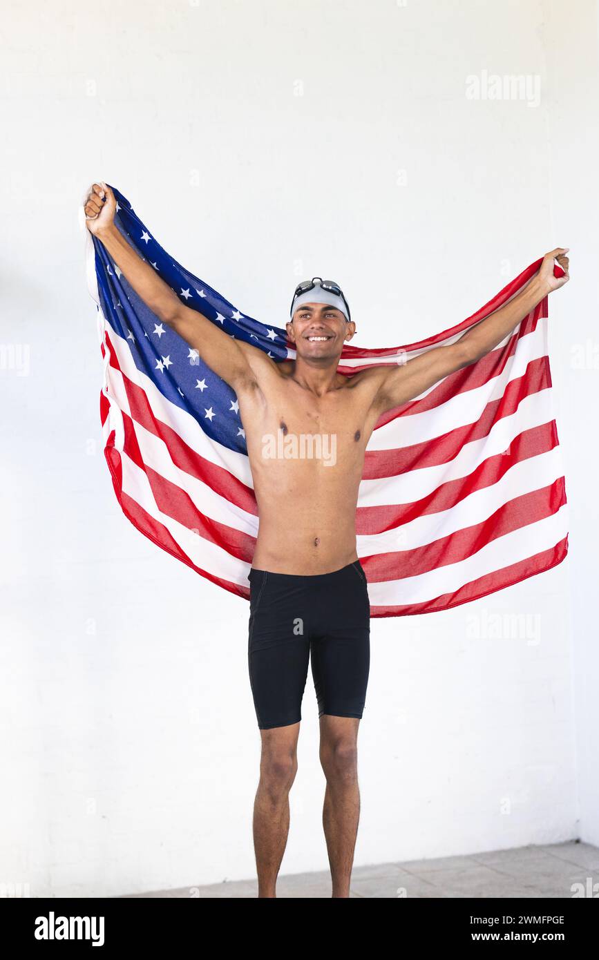 Junger männlicher Sportler, der mit birassischer Rasse schwimmt, feiert den Sieg in der amerikanischen Flagge Stockfoto