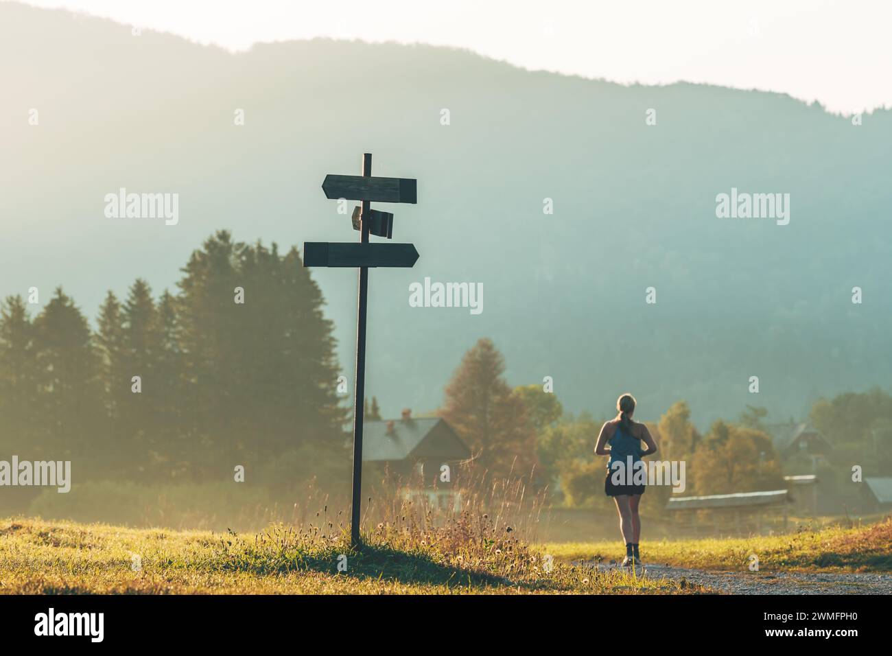 Morgendliche Joggingroutine, nicht erkennbare Joggingerin, die am Sommermorgen auf einem Schotterpfad durch die wunderschöne alpine Landschaft läuft Stockfoto
