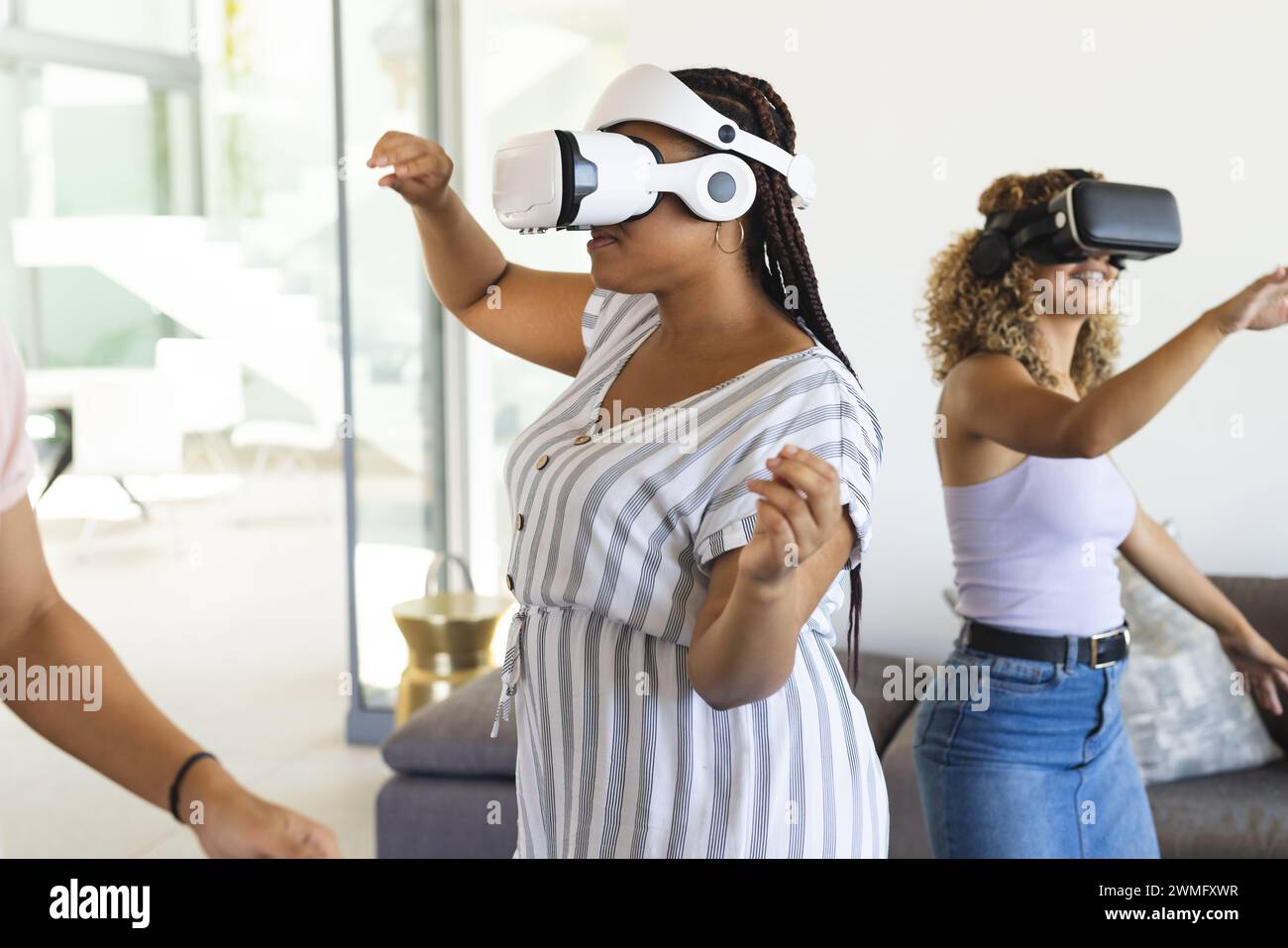 Junge, birassische Frauen genießen die virtuelle Realität zu Hause Stockfoto