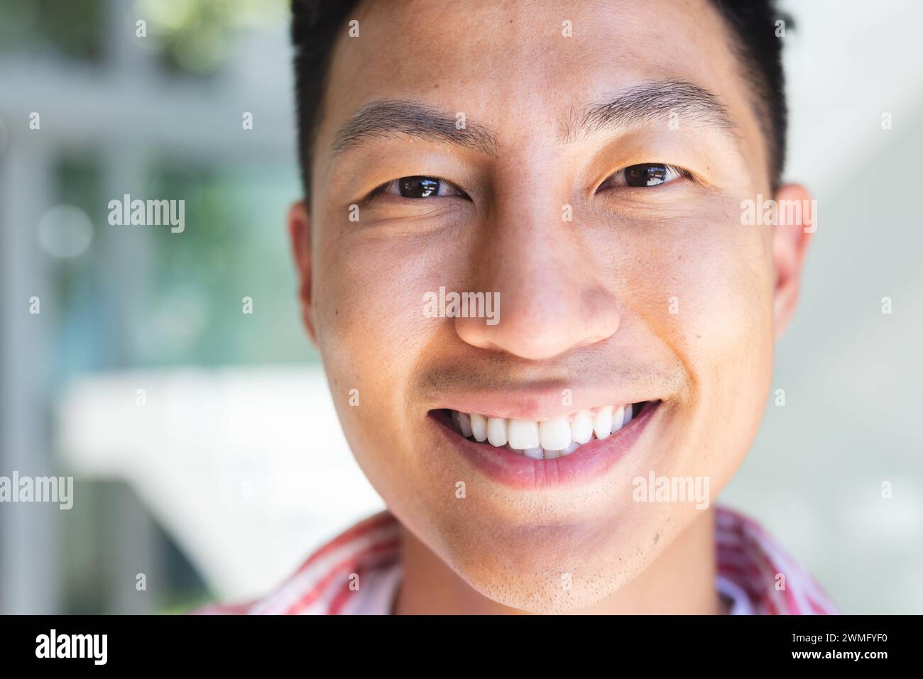 Nahaufnahme eines lächelnden jungen Asiaten draußen Stockfoto