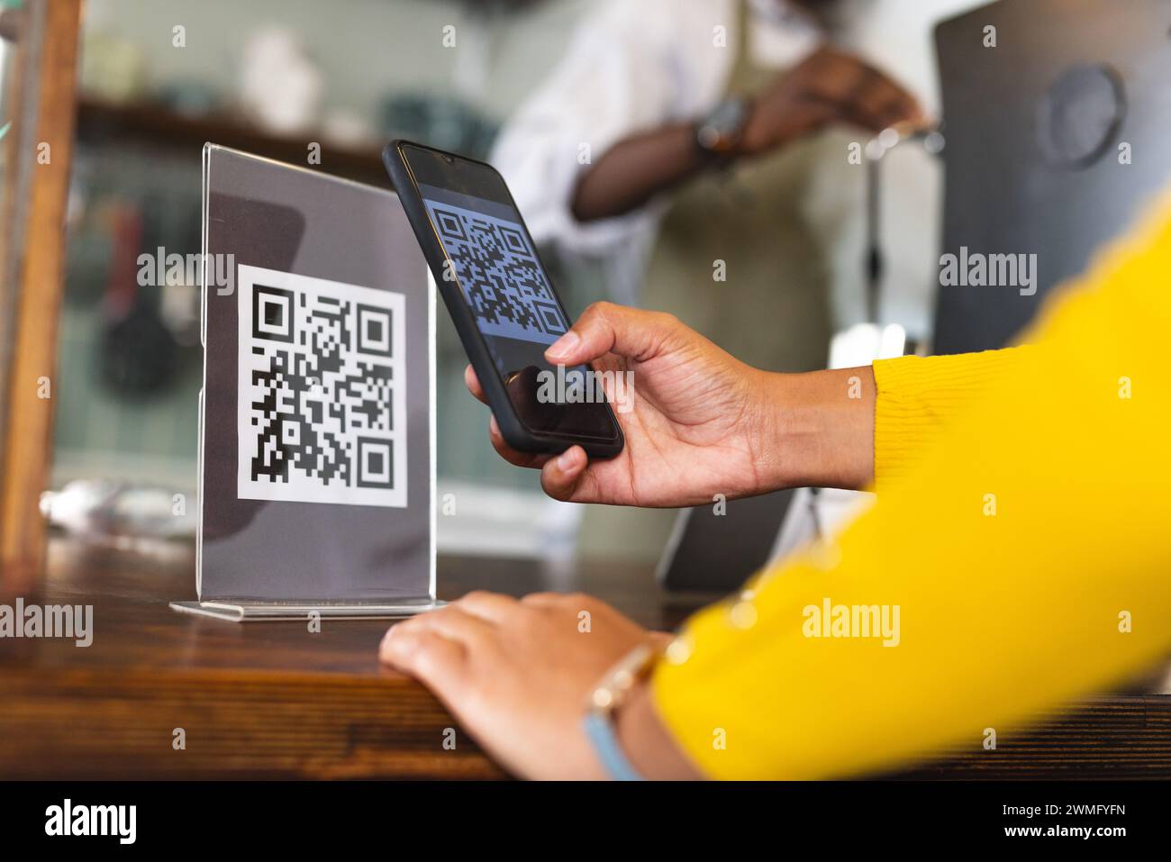 Eine Person scannt einen QR-Code an einer Kasse Stockfoto