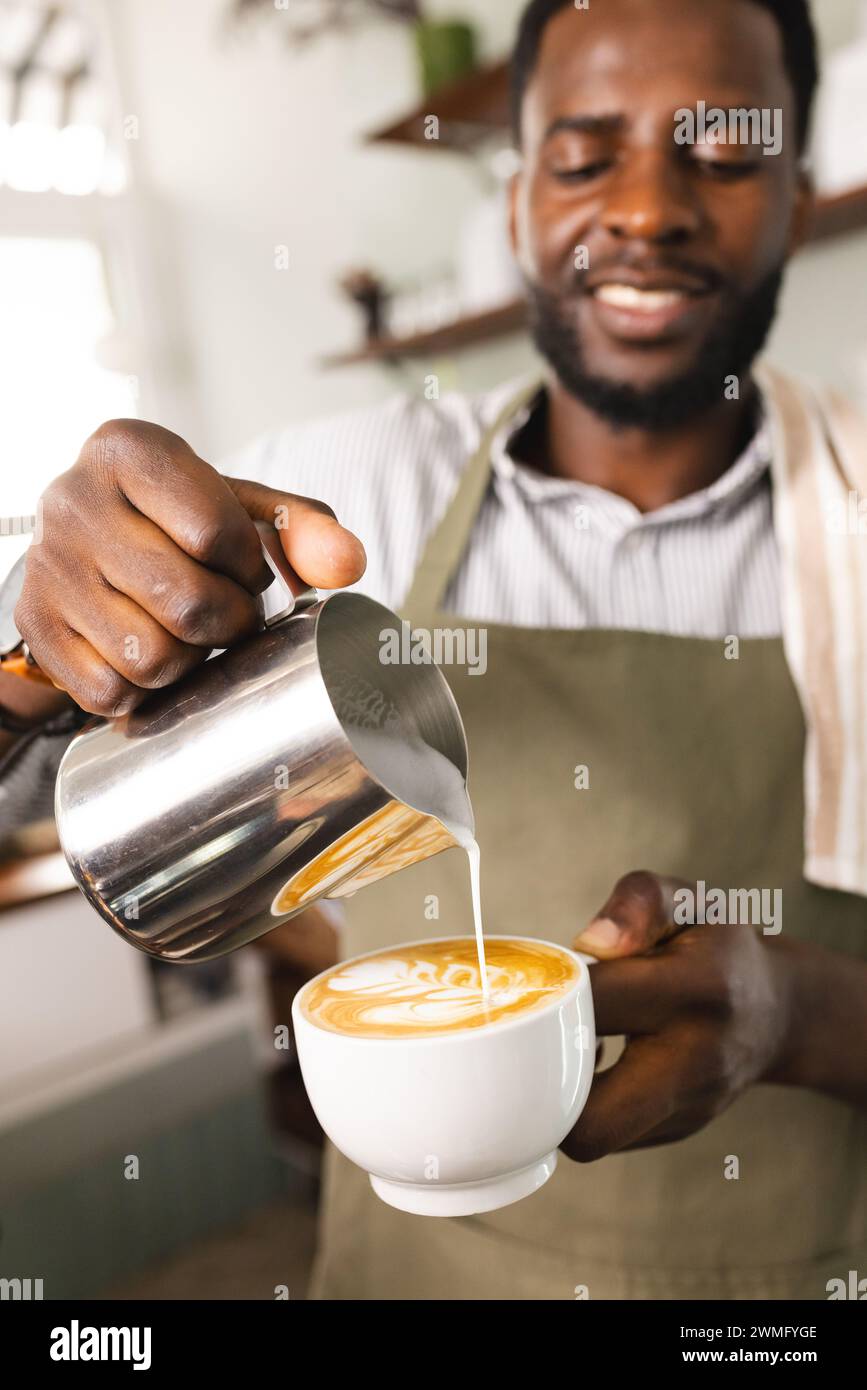 Der afroamerikanische Barista gießt Milch in einen Kaffee in einem Café Stockfoto