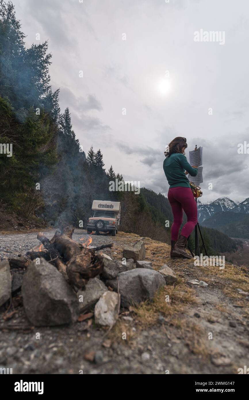 Frau spielt Saxophon neben dem Wohnmobil in den Bergen Stockfoto