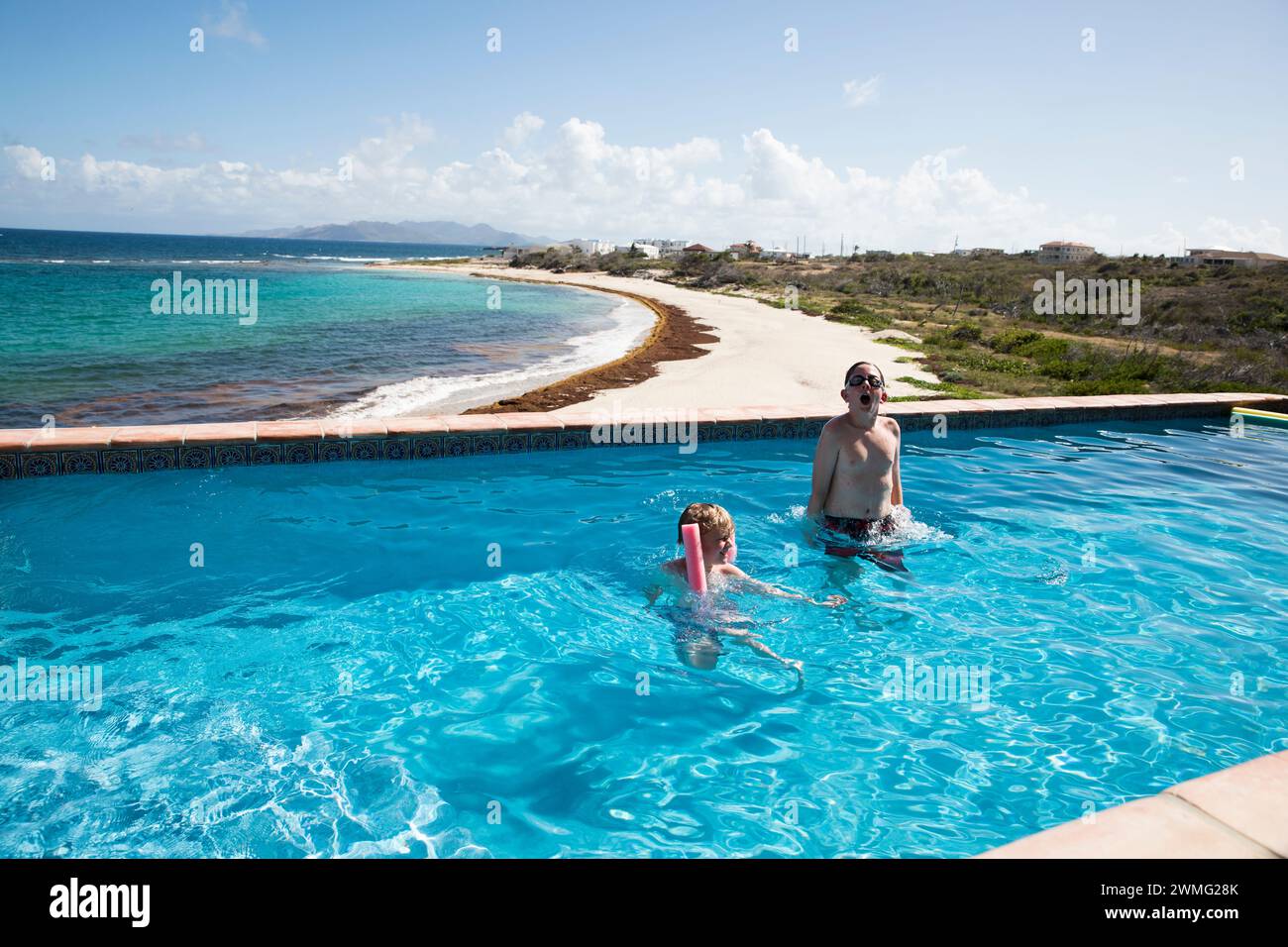 Aufrichtig verspielte Brüder im Infinity Pool im Karibikurlaub Stockfoto
