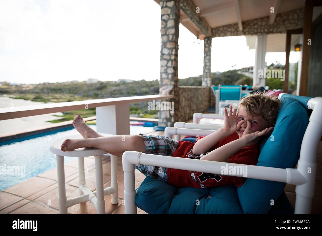 Junge macht Gesichter in Camera, auf der Terrasse im Karibikurlaub Stockfoto