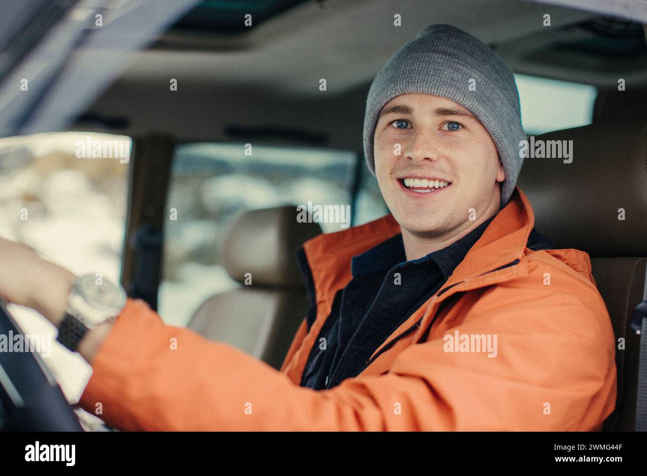 Ein kaukasischer junger Mann lächelt, während er in einem Fahrzeug sitzt. Stockfoto